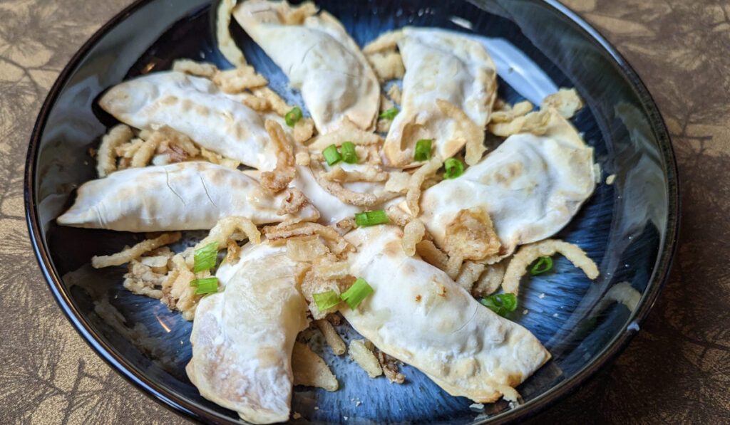 Air fryer perogies served with fried and green onions and horseradish sauce. 