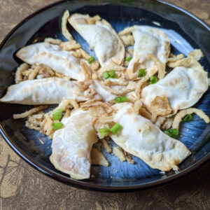 Mashed potato air fryer perogies garnished with green onion and crispy fried onions.