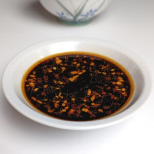 Stir fry sauce with a soy sauce and rice vinegar base in a bowl next to a decorative stir fry bowl.