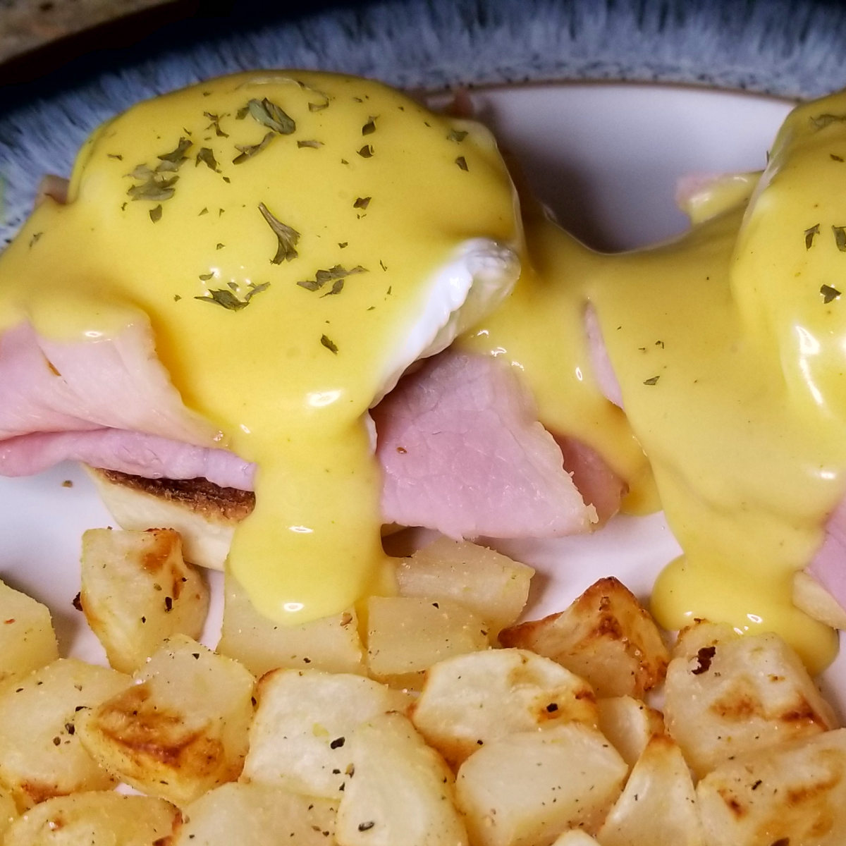 Eggs benedict with hollandaise oozing onto some home fries