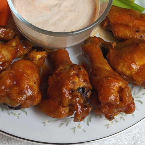 A close up of hot honey bourbon coated chicken wings served with ranch.