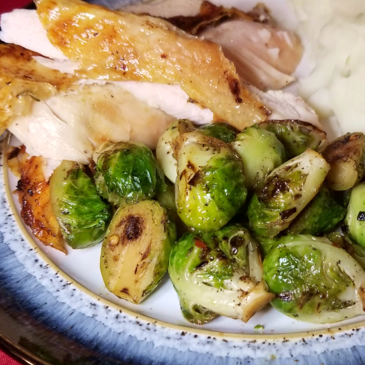 Charred brussels sprouts served with roasted chicken and mashed potatoes.