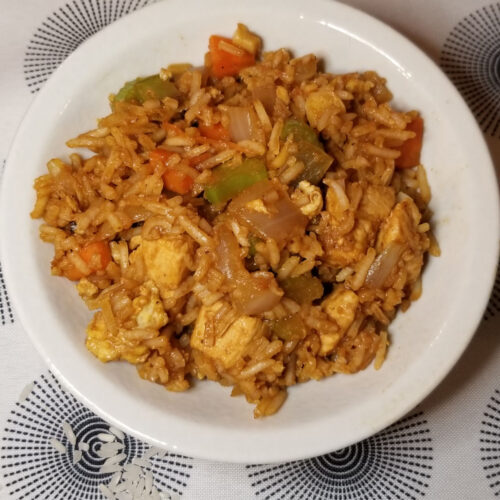 Chicken and vegetable fried rice in a small white bowl.