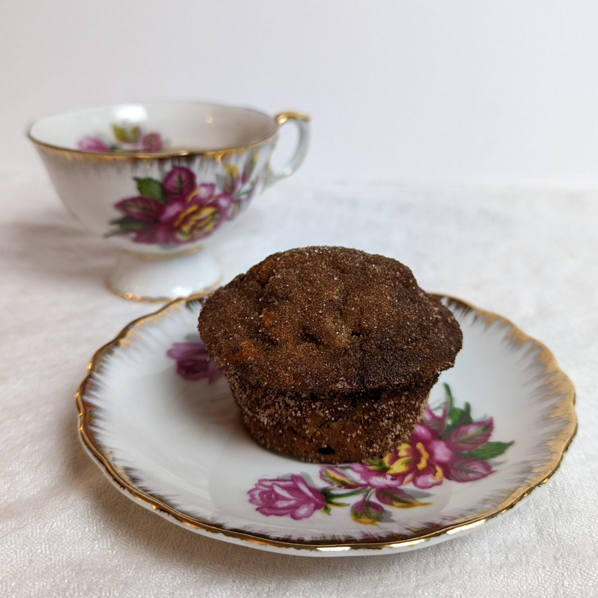 cinnamon sugar banana bread muffin on a floral plate with a matching tea cup.