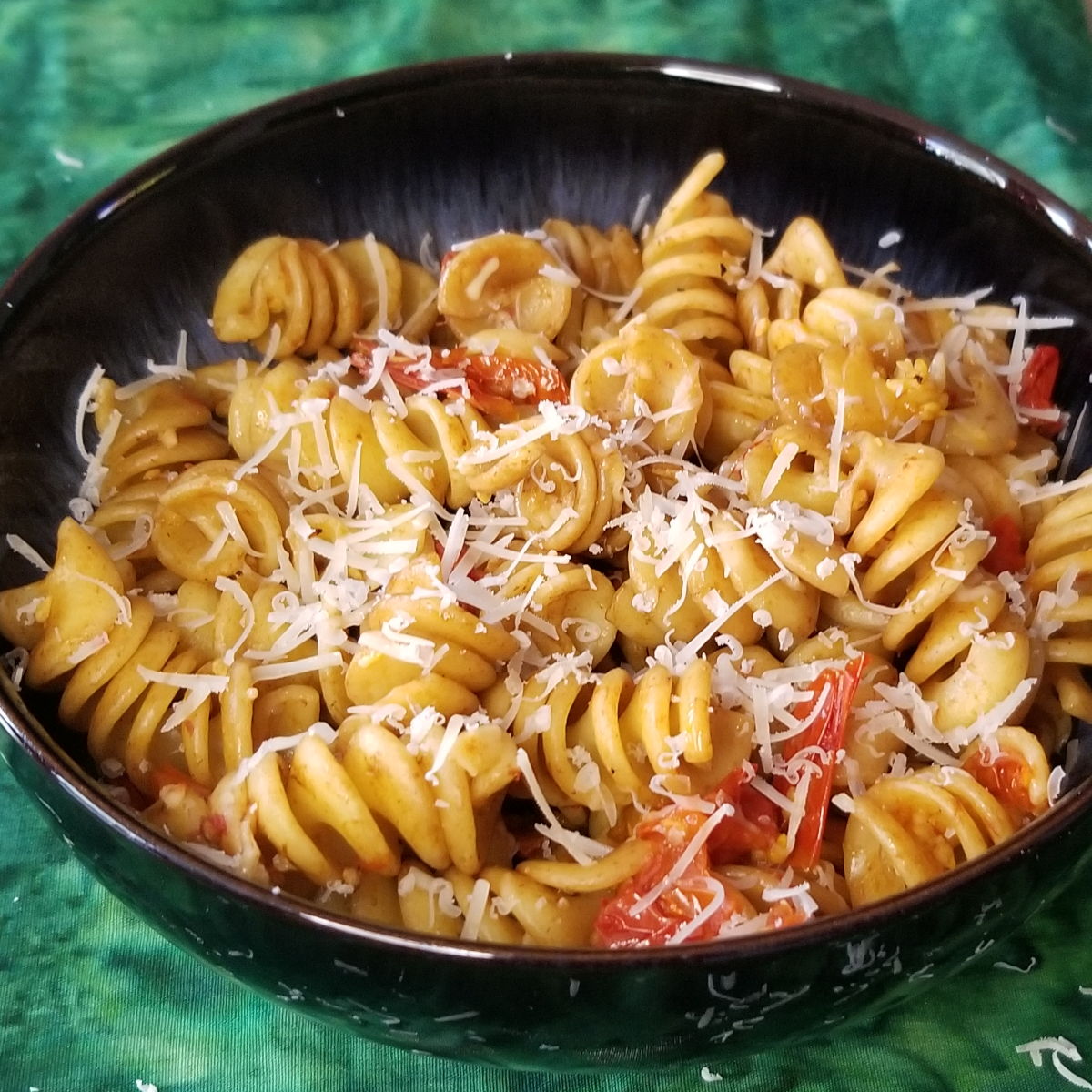 A bowl of cherry tomato pasta topped with parmesan.