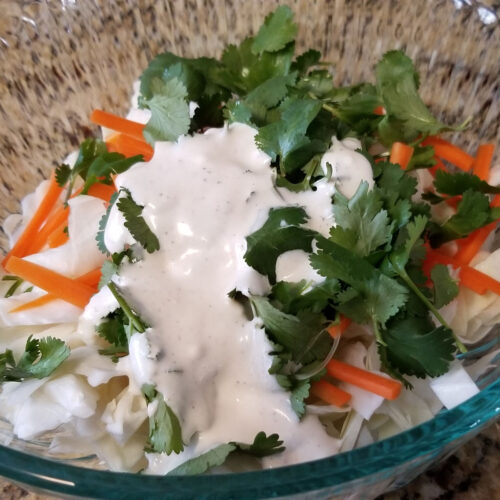 Cilantro, carrot, and cabbage with cilantro lime slaw dressing not yet fully mixed in.