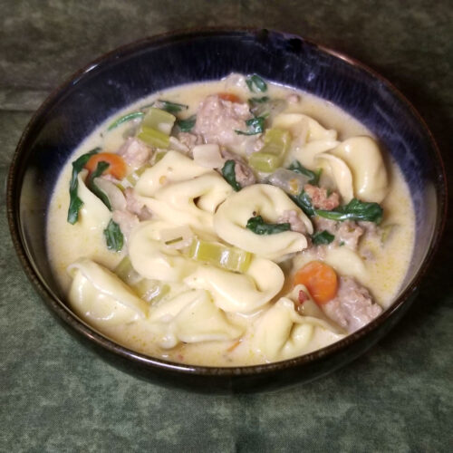 A close up of creamy sausage and tortellini soup