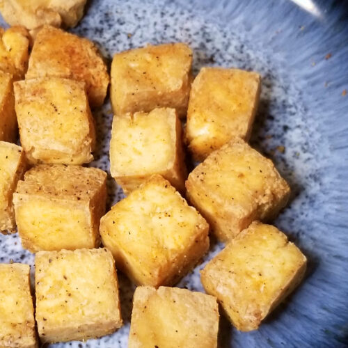 A close up of air fryer tofu on a blue plate.