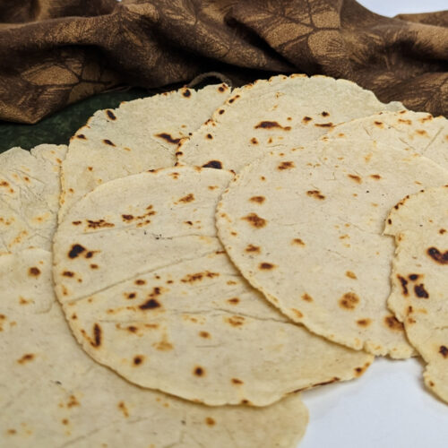 Corn tortillas stacked overlapping on a plate.