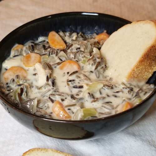 Minnesota wild rice soup being dipped into by French bread.